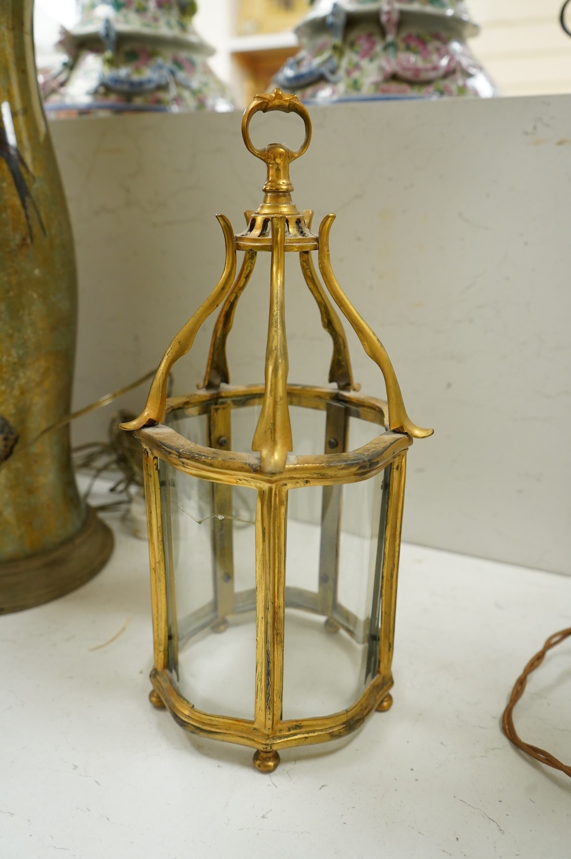 A pair of table lamps and shades, 92cm high, the lamps decorated in gold and green tones painted with birds and flowers, together with a small glass and brass hall lantern (3).